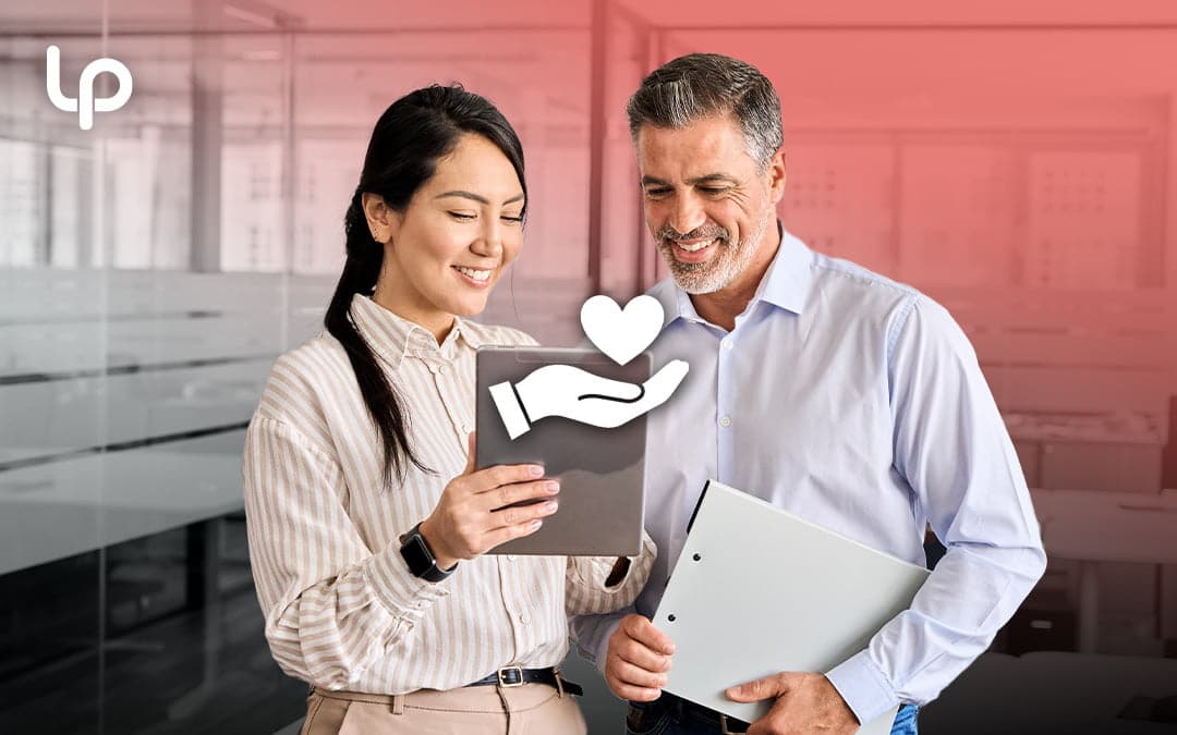 Woman holding tablet and showing man in conference room with giving heart hand icon in front of them