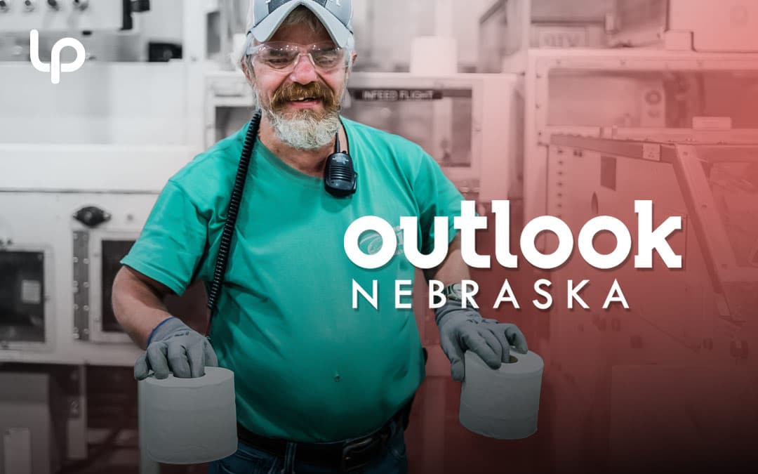 Blind employee at Outlook Nebraska posing with two toilet paper rolls in factory for PR case study