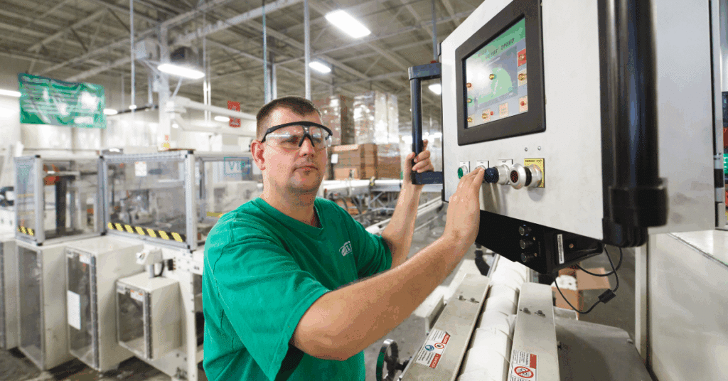 Blind employee pushing button on machine in toilet paper assembly line at Outlook Nebraska factory