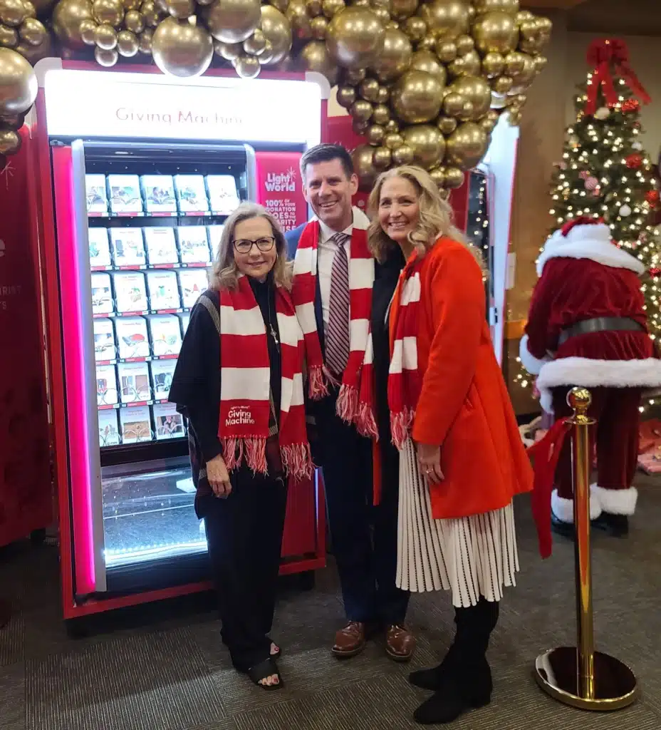 Governor, First Lady Pillen, and another guest posing in front of Giving Machine Omaha at 2024 Westroads Mall PR event