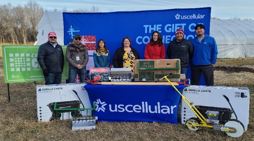 Seven people standing behind full UScellular donation table for Gift of Connectionevent