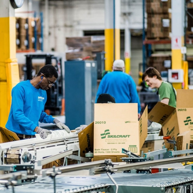 Outlook Enrichment workers in the warehouse on the assembly line packing toilet paper rolls and Skilcraft cardboard boxes in Nebraska