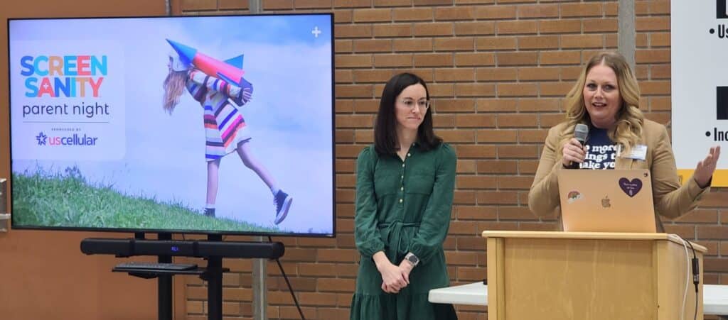Woman speaking at podium with another woman to the left and a slideshow for Screen Sanity Parent Night x UScellular Global Day of Unplugging PR campaign