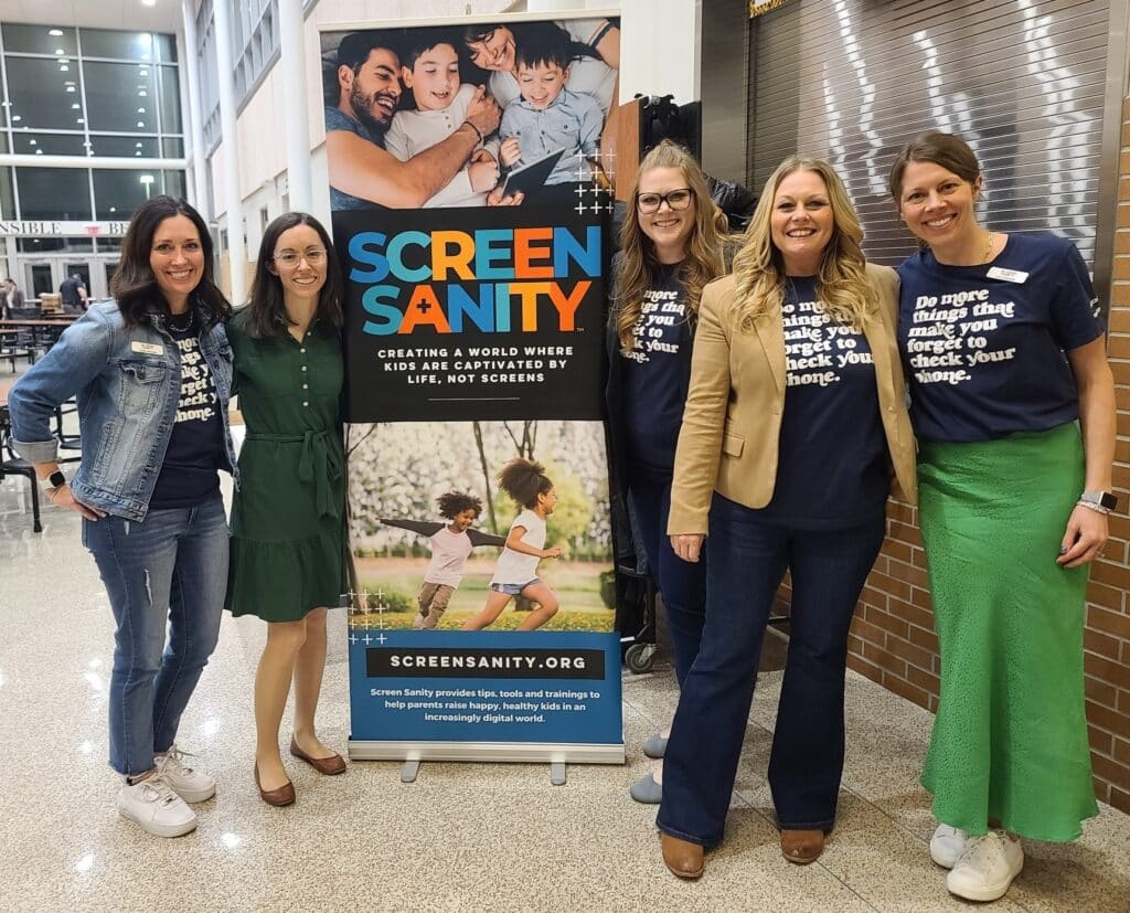 Kathleen Holtschneider and Jenae Bradley with Screen Sanity group in front of Screen Sanity Parent Night event poster