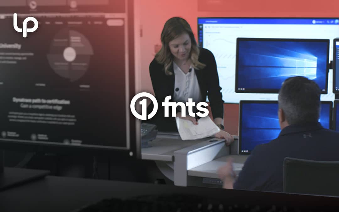 FNTS team members work together in an office with computer monitors displaying dashboards and analytics