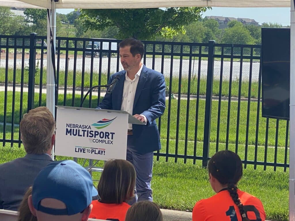 Speaker presenting at an outdoor press event for the Nebraska MultiSport Complex