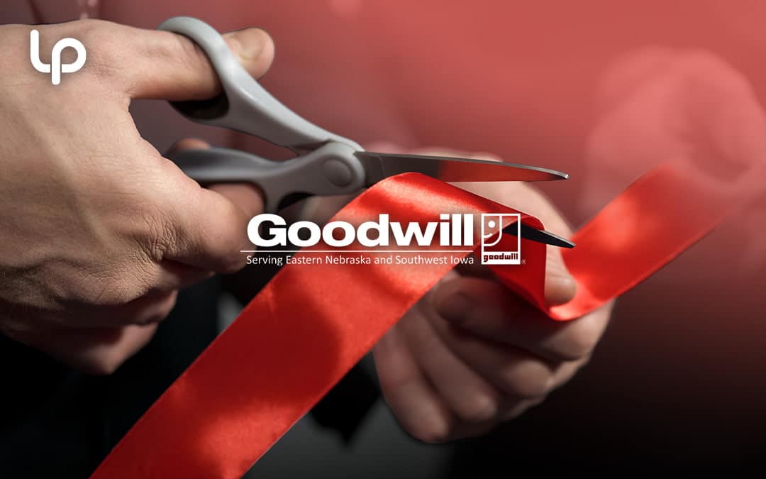 Close-up of scissors cutting a red ribbon at an event.