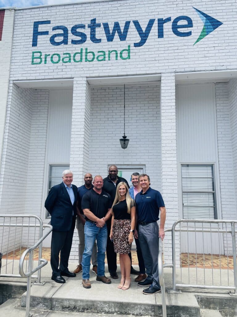 Local mayor and Fastwyre Broadband representatives posing outside a branded office location.